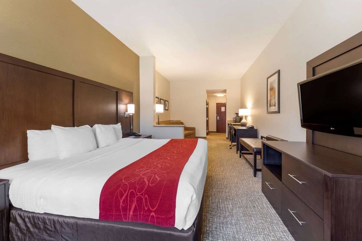 Une chambre d’hôtel avec un grand lit, un bureau, une chaise, une télévision et une armoire.
