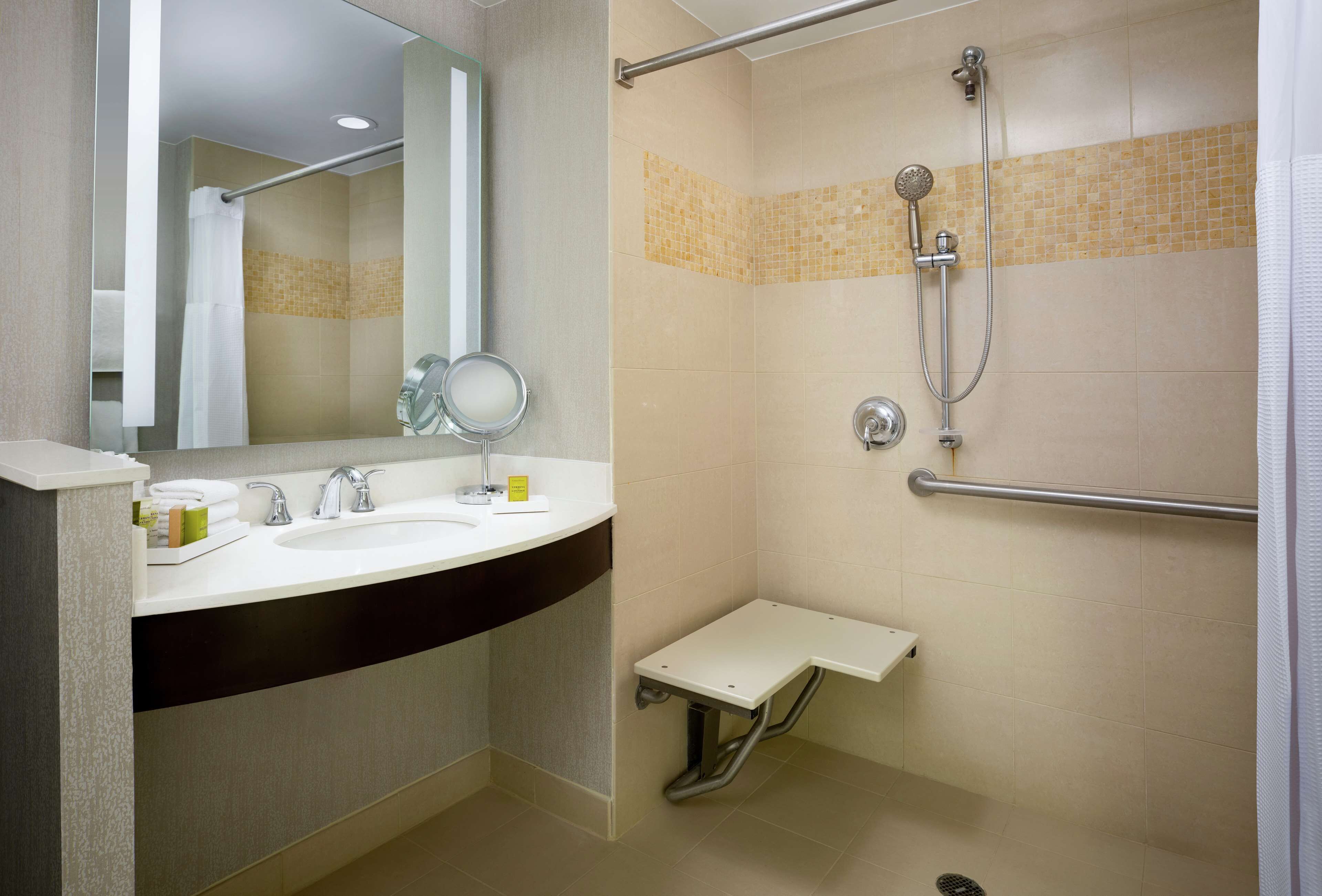A modern bathroom with a sink, mirror, and shower.