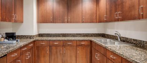 Una cocina con gabinetes de madera, encimeras de granito y un fregadero de acero inoxidable.
