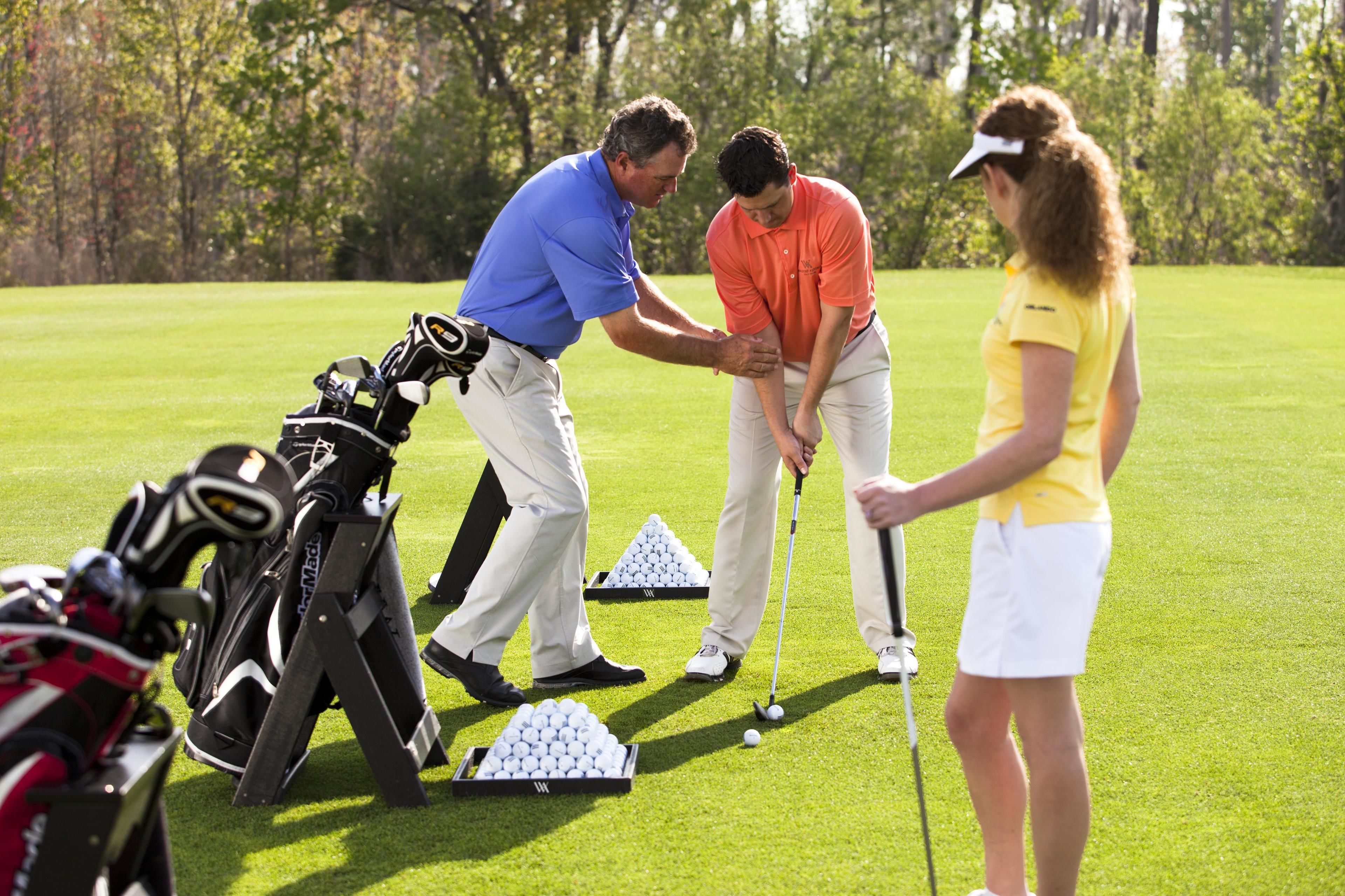 A golf course with a putting green, golf bags, and a golf ball.