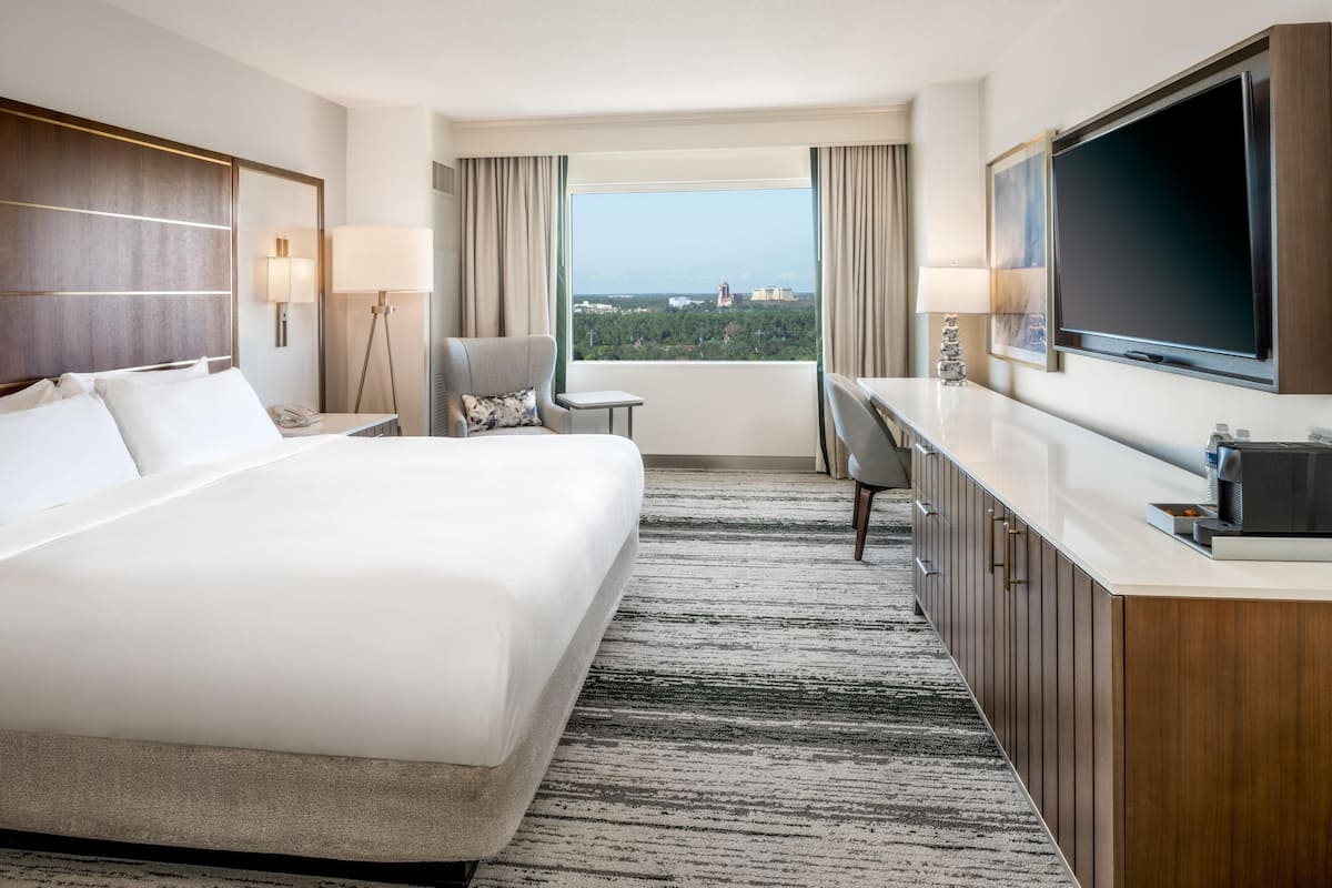 Hotelkamer met een groot bed, een bureau, een stoel, een televisie en uitzicht op de stad.