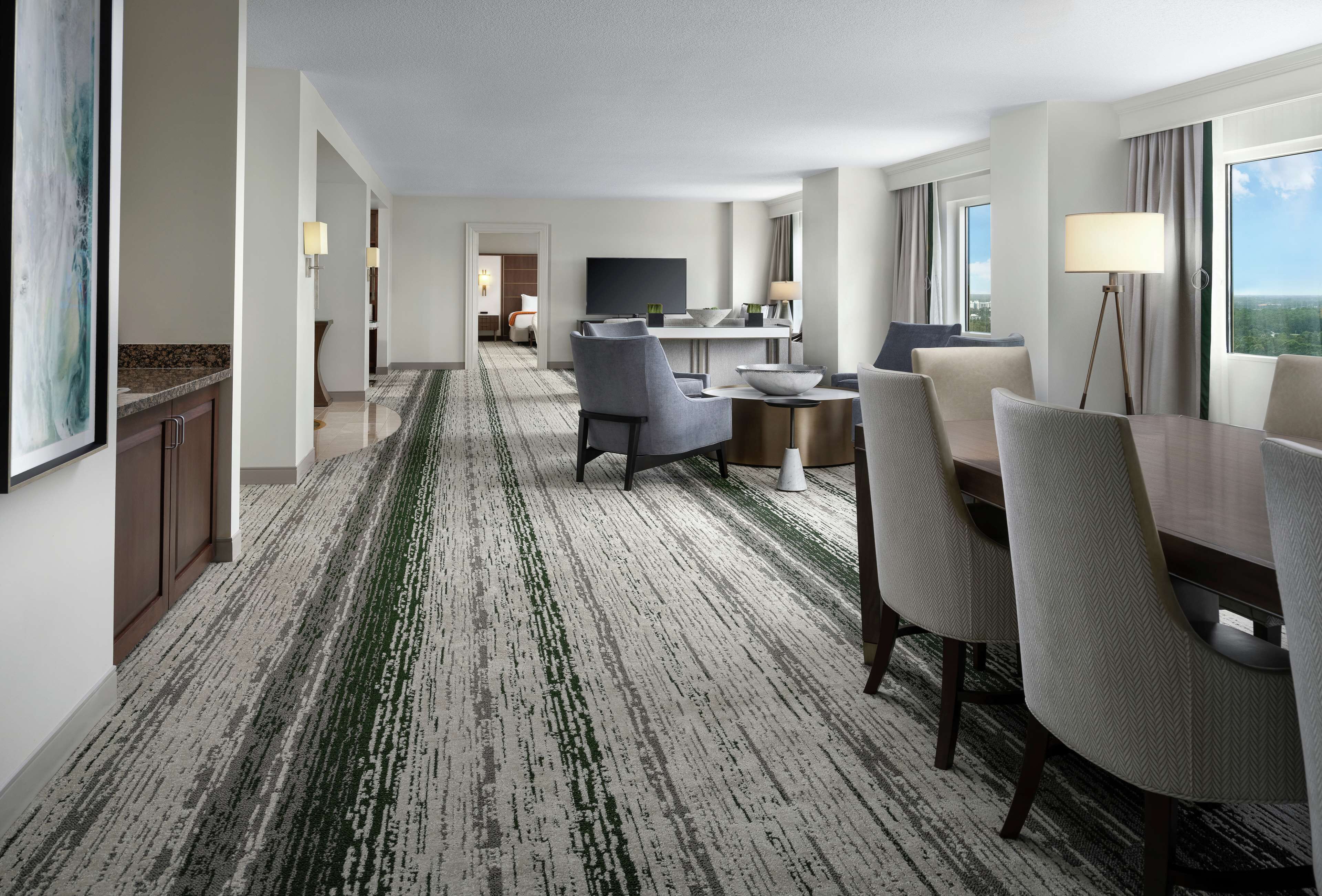 A hotel room with a dining area, a TV, and a view of the city.