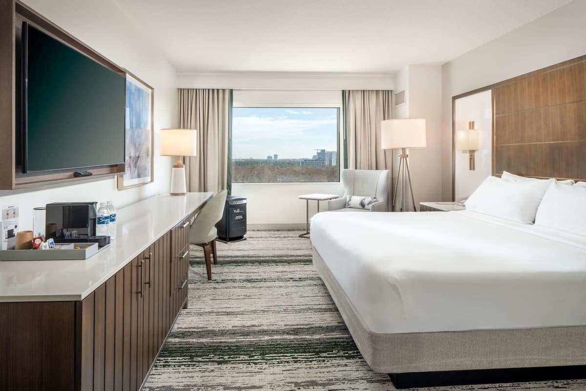 Ein Hotelzimmer mit Bett, Schreibtisch, Stuhl, Fernseher und Blick auf die Stadt.
