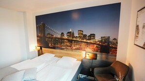 A hotel room with a large bed, a chair, and a cityscape mural on the wall. - Vildbjerg Hotel (Vildbjerg)