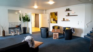 A modern living room with a sofa, chairs, a coffee table, and decorative items. There is a staircase to the right and a door leading to another room. - Vildbjerg Hotel (Vildbjerg)