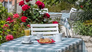 A table set outdoors with a checkered tablecloth, a croissant, a glass of orange juice, and a pitcher. - Villa Doris (Dubrovnik)