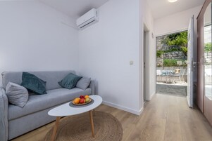 Quarto triplo clássico, terraço, vista parcial para o mar | Área de estar | TV de tela plana 82 cm com canais a cabo, TV