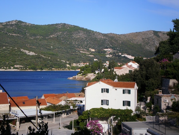 A coastal town with a white building, a view of the sea, and hills in the background. - Villa Doris (Dubrovnik)