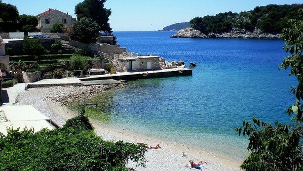 A coastal area with a stone building, a dock, and a clear blue sea. - Villa Doris (Dubrovnik)