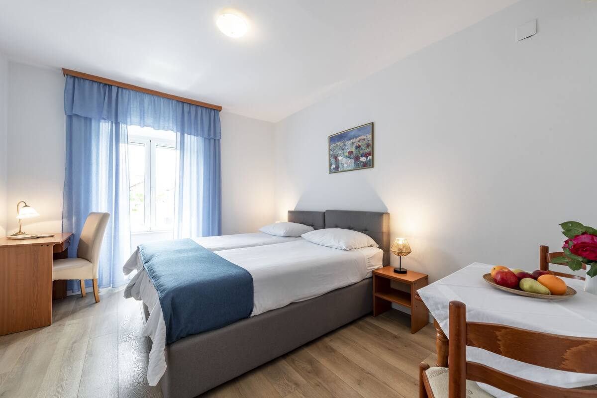 A bedroom with a bed, bedside tables, a desk, and a chair.