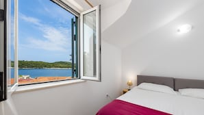 A bedroom with a large window offering a view of a body of water and greenery. - Villa Doris (Dubrovnik)