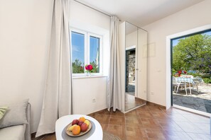 A modern room with a large window, a dining area with a table and chairs, and a fruit bowl on a small table. - Villa Doris (Dubrovnik)