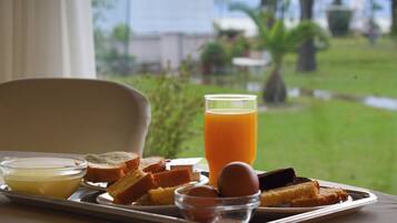 A tray with toast, eggs, and orange juice on a table with a view of a garden.