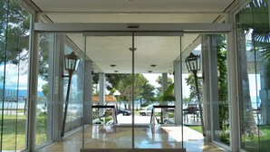 A glass door entrance with a view of a parking area and outdoor seating. - Theoxenia (Mesolongi)