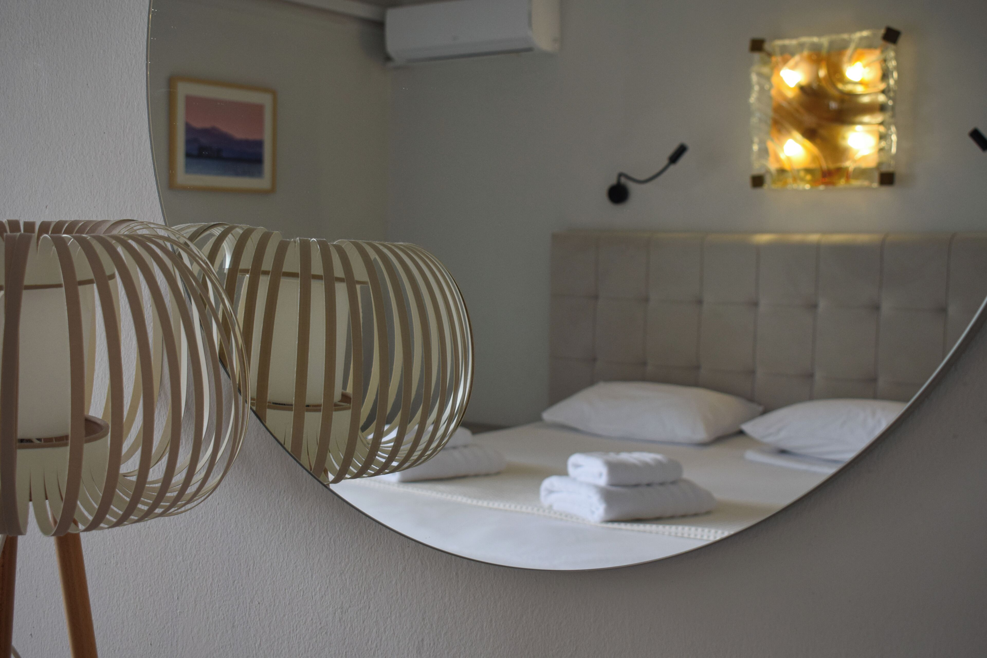 A hotel room with a bed, a wall-mounted light fixture, and a framed picture on the wall.