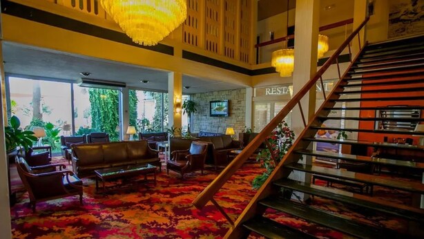 A lobby with a staircase, seating area, and a restaurant sign. - Theoxenia (Mesolongi)