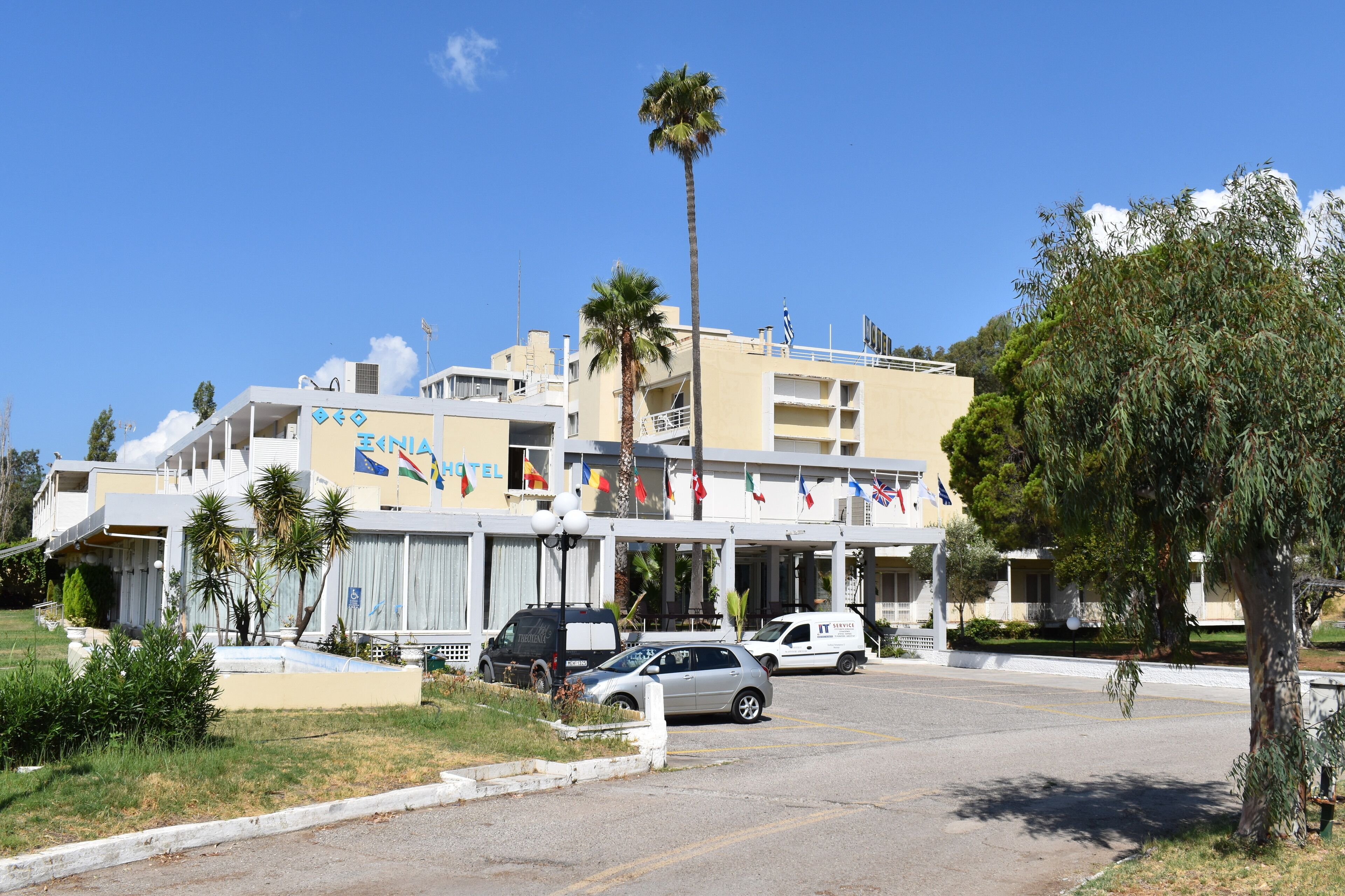 Un hotel de diseño moderno, con una entrada destacada, varios balcones y una zona de estacionamiento.