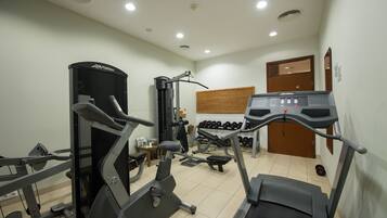 A gym with cardio machines, weightlifting equipment, and neatly arranged dumbbells.