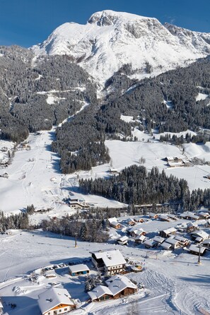 Een met sneeuw bedekte berg met een skigebied op de voorgrond, met houten chalets en skipistes.