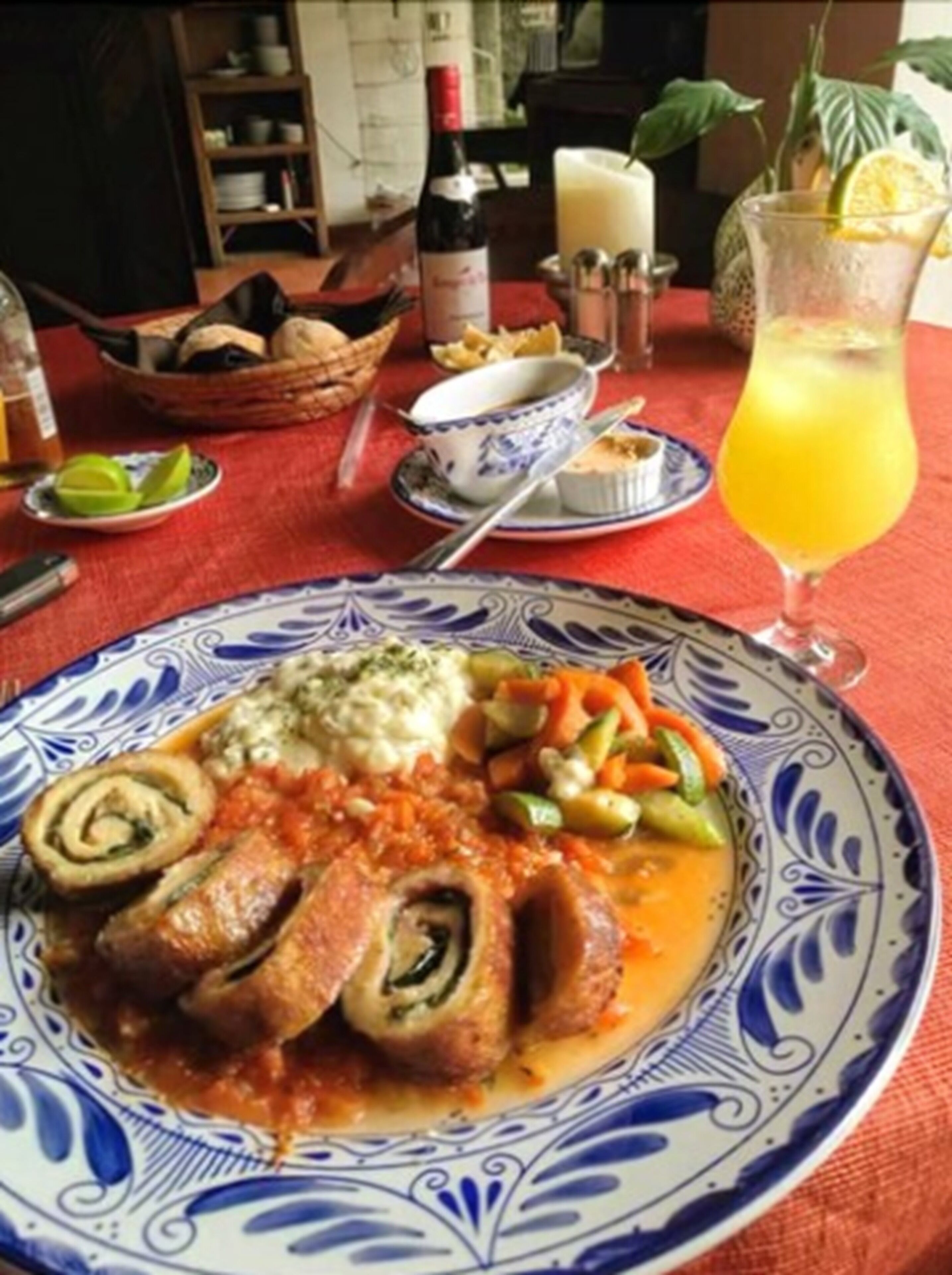 A dining table with a plate of food, a bottle, and a glass of orange juice.