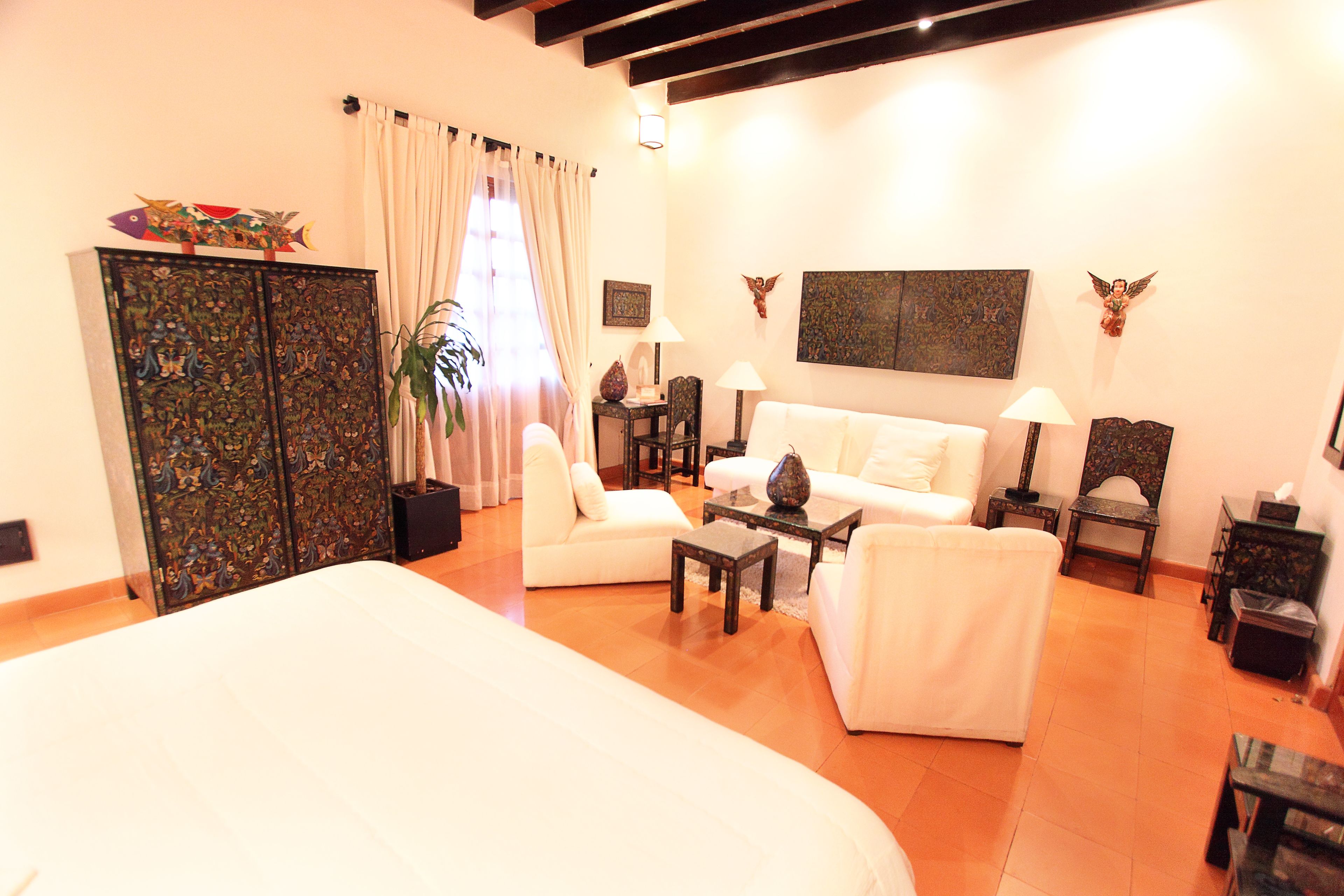 A spacious living area with a large bed, white sofas, a coffee table, and decorative items.