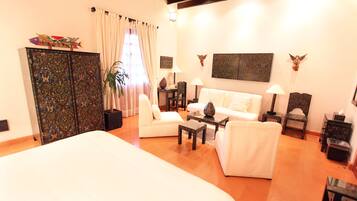 A spacious living area with a large bed, white sofas, a coffee table, and decorative items.