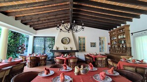 Un comedor con mesas dispuestas para una comida, una chimenea y una colección de cerámica en la pared.
