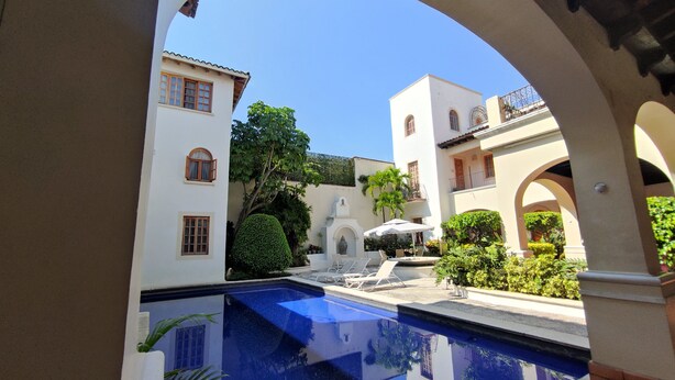 Un patio con piscina, edificios blancos y arcos.