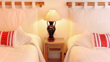 Een hotelkamer met twee bedden, een lijst met een textielkunstwerk, een bedlamp en een houten plafond.