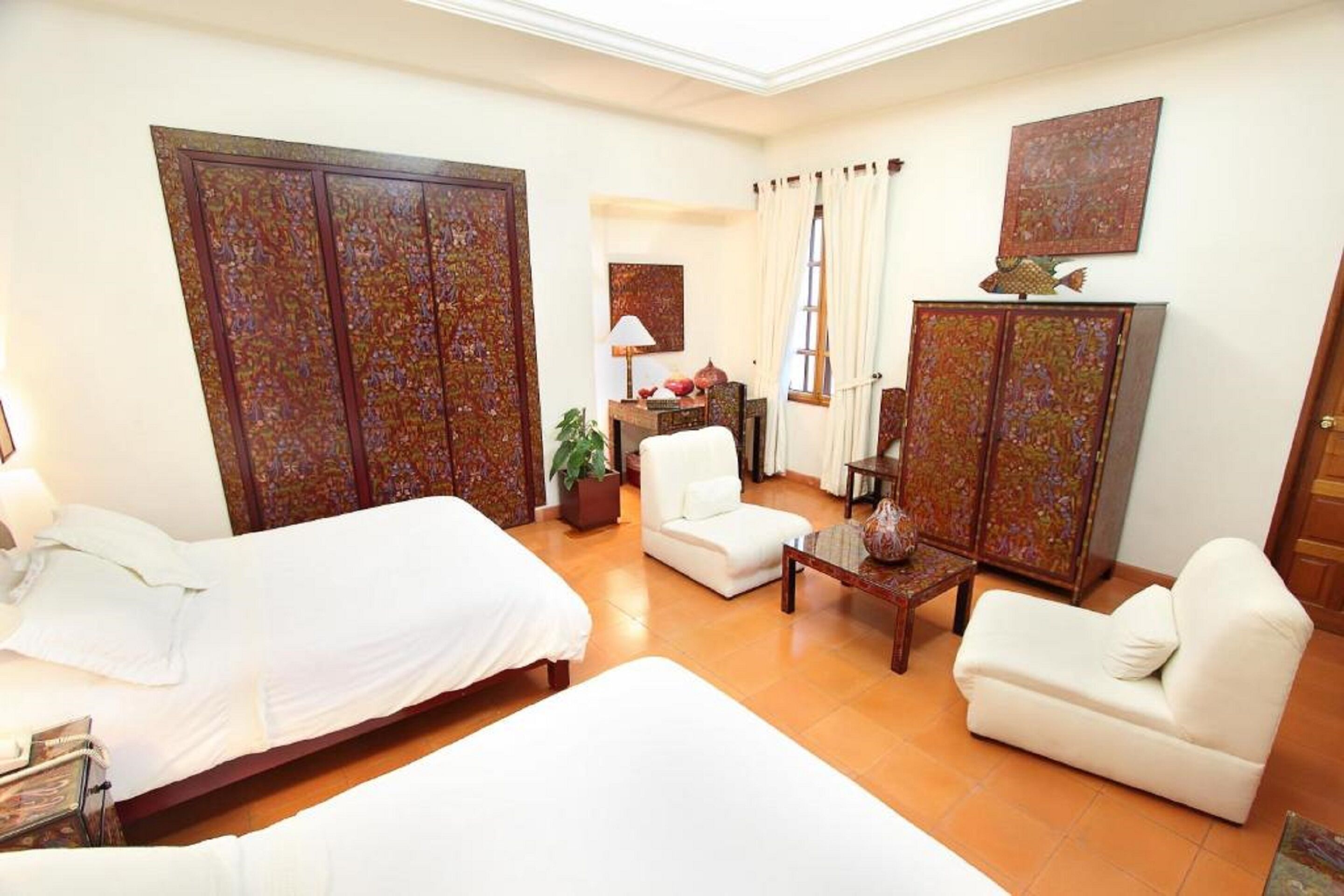 A hotel room with two beds, a sofa, a chair, a desk, and a cabinet.