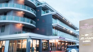 A multi-story building with a glass facade, multiple balconies, and a ground-level entrance with signage for Crowne Plaza London-Kingston.