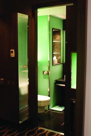 Un baño con pared verde, inodoro blanco, espejo y balanza.