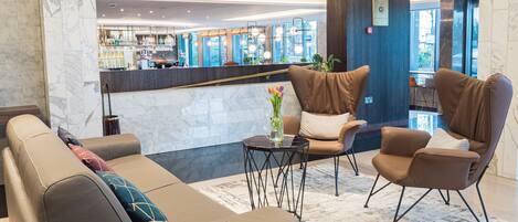 Eine Lobby mit Sitzgelegenheiten, einer Rezeption und einer Bar.