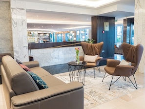 A lobby with a seating area, a reception desk, and a bar.