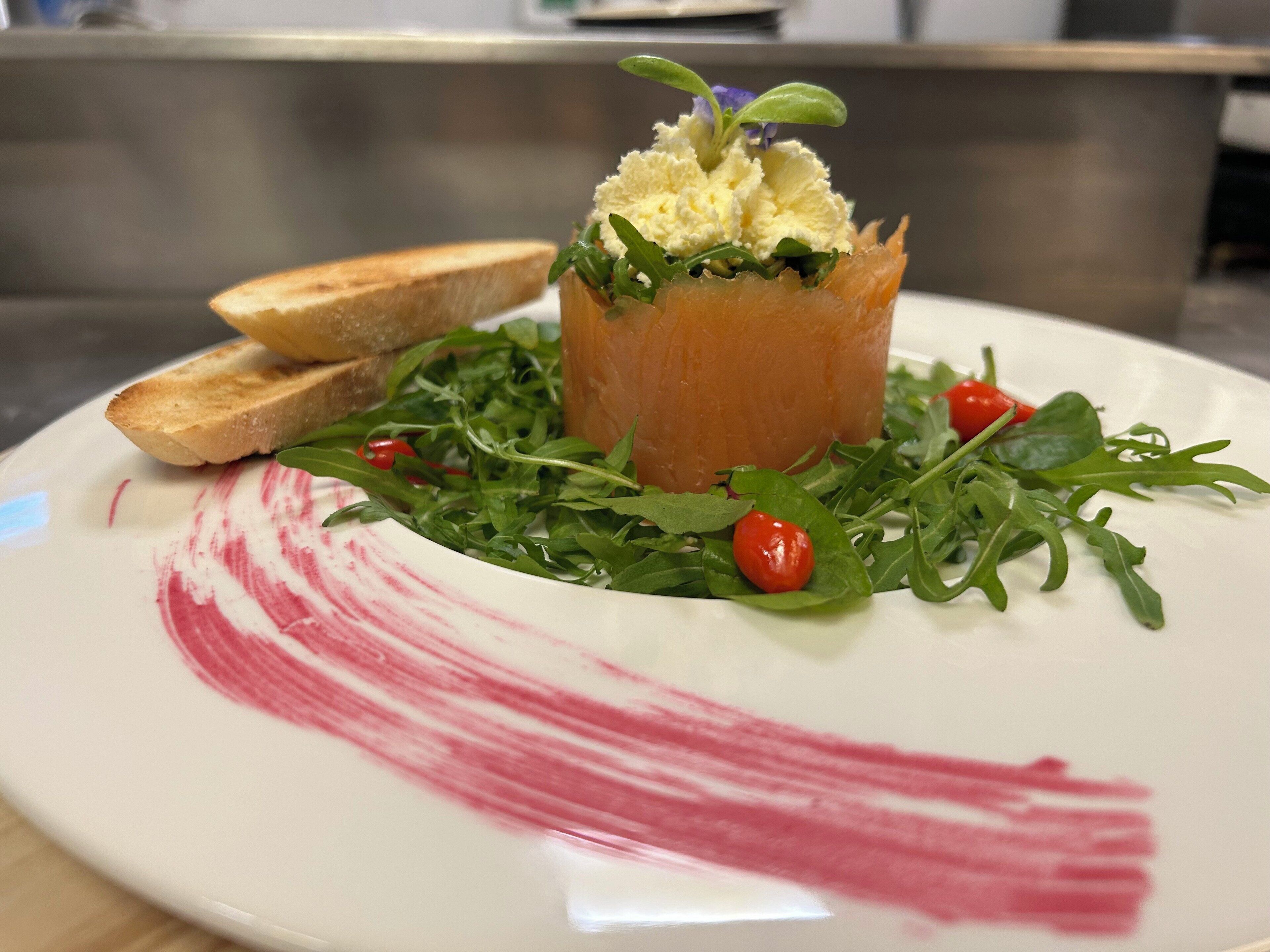 Une assiette contenant un plat, quelques légumes verts et une marque rouge sur l’assiette.