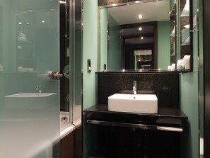 A modern bathroom with a glass shower enclosure, a white sink, and a mirror above it.