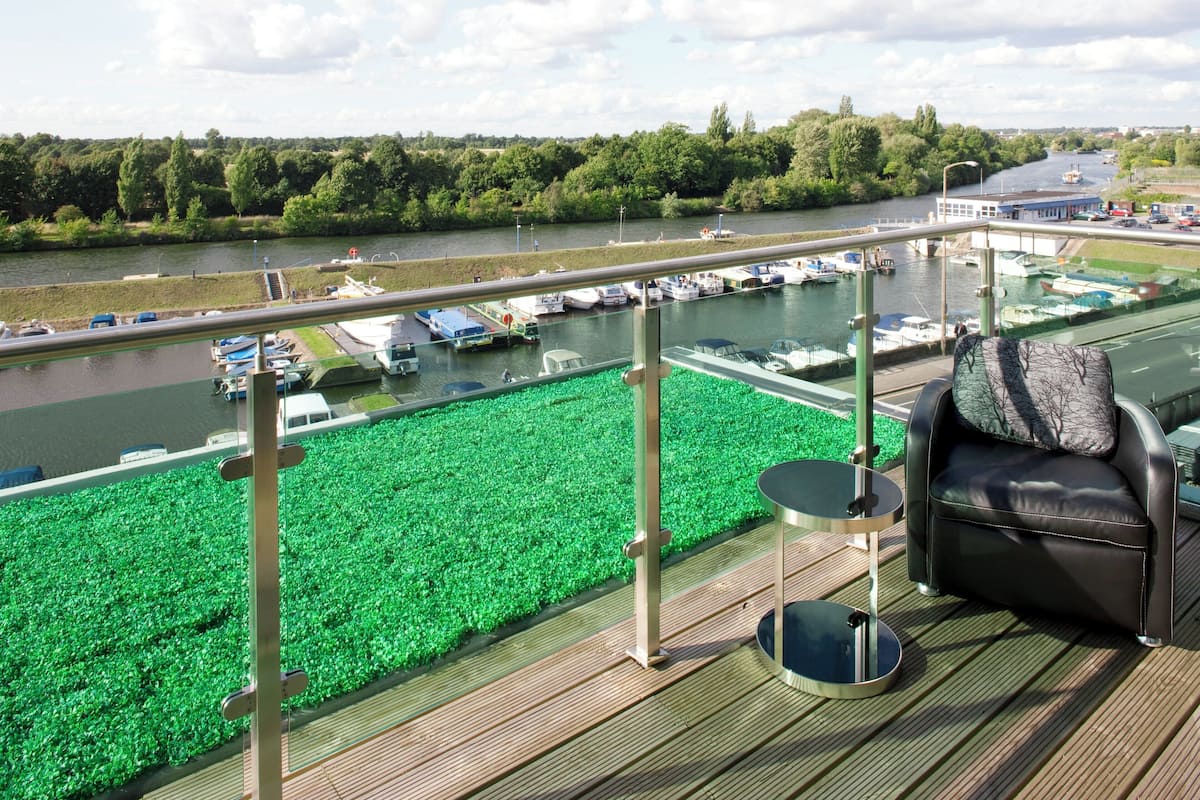 Een balkon met uitzicht op een rivier, boten en begroeiing.