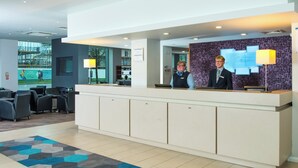 A hotel reception area with a modern design, including a reception desk, seating area, and a view of the outside. - Holiday Inn Express Lincoln City Centre by IHG (Lincoln)