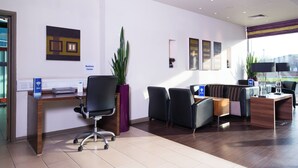 A modern office space with a reception desk, seating area, and a large window providing natural light. - Holiday Inn Express Lincoln City Centre by IHG (Lincoln)