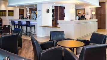 A bar area with a counter, bar stools, and a seating area with tables and chairs.