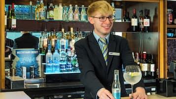 Un comptoir avec une variété de bouteilles d’alcool et une personne en costume.
