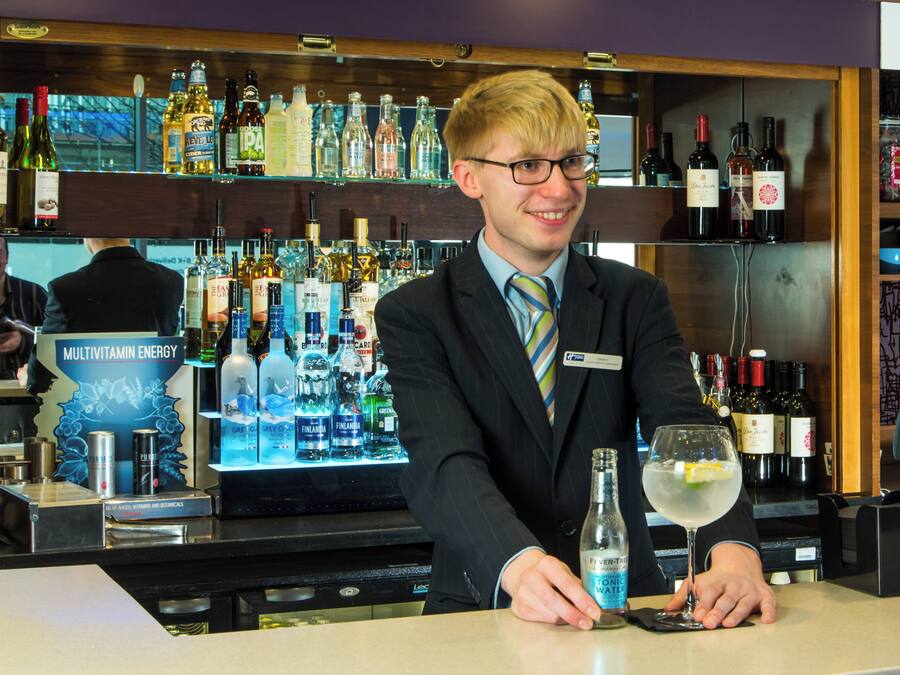 Un comptoir avec une variété de bouteilles d’alcool et une personne en costume.
