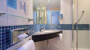 Un baño con cabina de ducha de vidrio, un lavabo con toalla y un espejo.