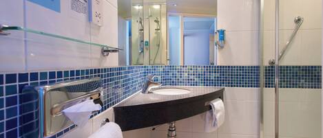Un baño con cabina de ducha de vidrio, un lavabo con toalla y un espejo.