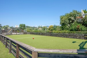A sports court with a wooden fence, a red ball, and a goal post.