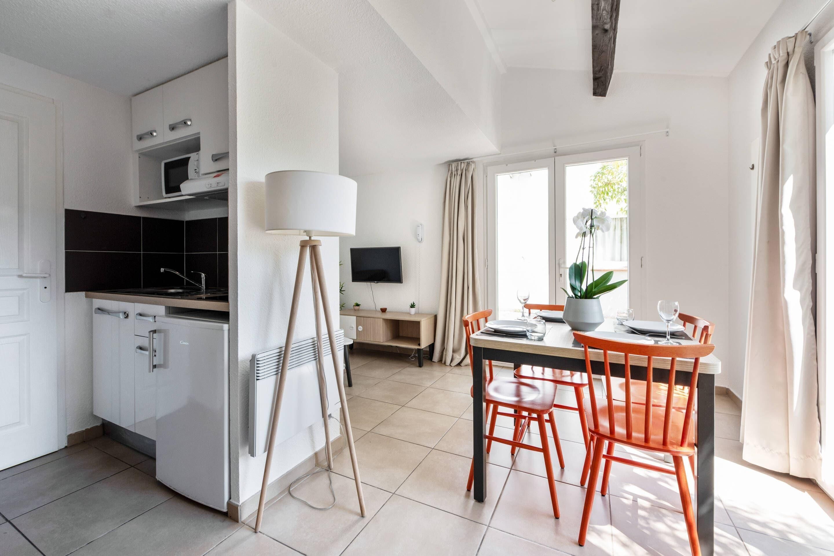 A modern kitchen with white cabinets, a microwave, and a dining area with a table and chairs.