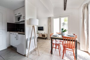 Una cocina moderna con armarios blancos, un microondas y un comedor con mesa y sillas.