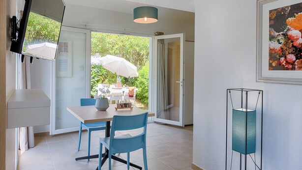 Un espace repas comprenant une table, des chaises et un luminaire suspendu au plafond.