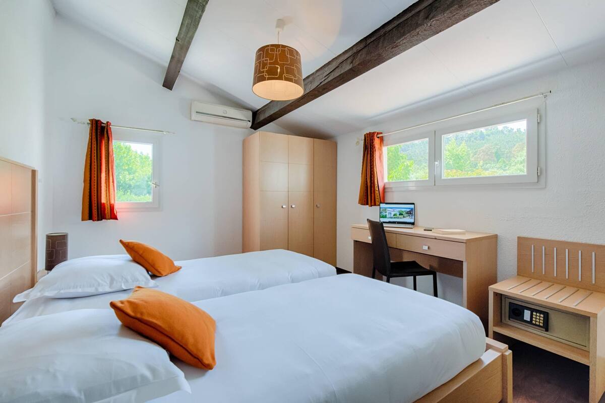 Une chambre d’hôtel avec deux lits, un bureau, une chaise, un ordinateur et un four à micro-ondes.