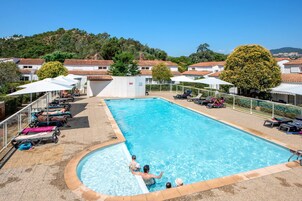 Una piscina al aire libre de temporada, sombrillas